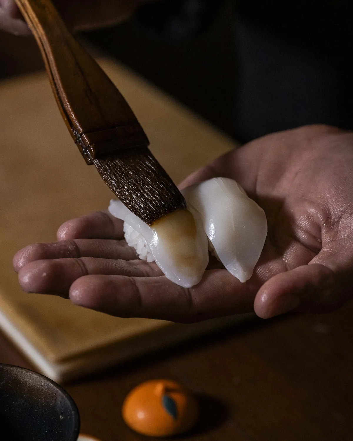 Chef's hands finishing a piece of nigiri
